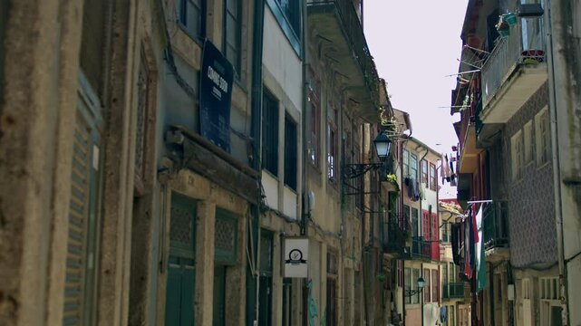 A narrow street view of Porto with balconies and laundry etc.