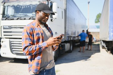 Professional truck driver holding smart phone in front of the trucks