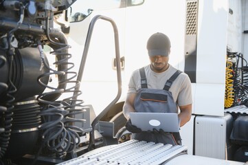 Truck repair service. African american Mechanic makes computer diagnostic of the semitruck