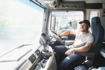 Professional african american truck driver in casual clothes driving truck vehicle going for a long transportation route