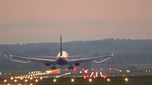 The plane lands at the airport. Commercial Jet Airplane Landing in airport runway at sunset. 