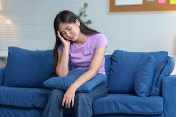Obraz premium A woman with a sneeze is feeling unwell. Runny nose and sneezing, stomach ache, sore throat, fatigue in the living room on the sofa in the house. Feeling bad and having allergies treatment concept.