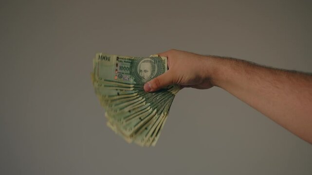 Man shaking a large amount of 100,000 guarani bills, a sign of abundance and happiness