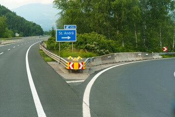 A winding road with a highway sign pointing towards St. Andra surrounded by lush greenery under an...