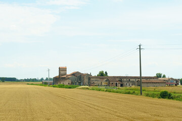 A sunlit landscape reveals abandoned farmland and a weathered building in the distance beneath a...