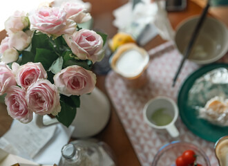 Setting of breakfast includes coffee, toast, samll potatos on table at home,pink rose