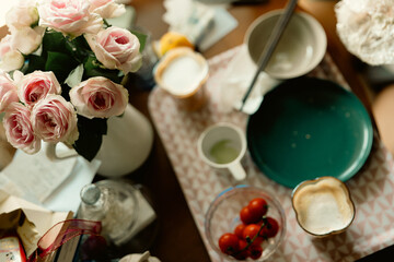 Setting of breakfast includes coffee, toast, samll potatos on table at home,pink rose