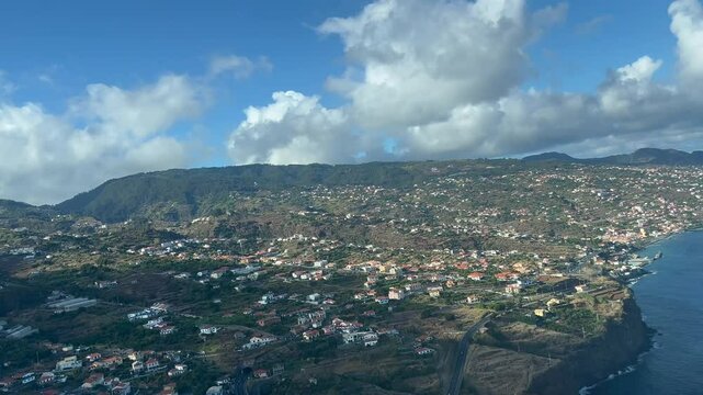 Pilot POV FPV to Madeira Funchal airport as seen from a jet cockpit. Aerial view of south coast of Madeira and the runway airport with a blue sky with some clouds. 4K 60FPS