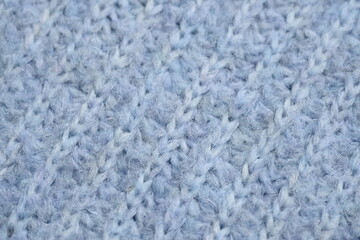 macro texture of woolen blue crocheted sweater as background, close-up of blue crocheted front surface, woolen texture of woolen wool, knitted front surface