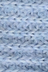 macro texture of woolen blue crocheted sweater as background, close-up of blue crocheted front surface, woolen texture of woolen wool, knitted front surface