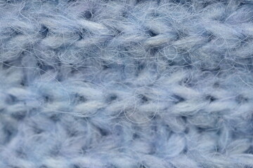 macro texture of woolen blue crocheted sweater as background, close-up of blue crocheted front surface, woolen texture of woolen wool, knitted front surface