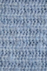 macro texture of woolen blue crocheted sweater as background, close-up of blue crocheted front surface, woolen texture of woolen wool, knitted front surface