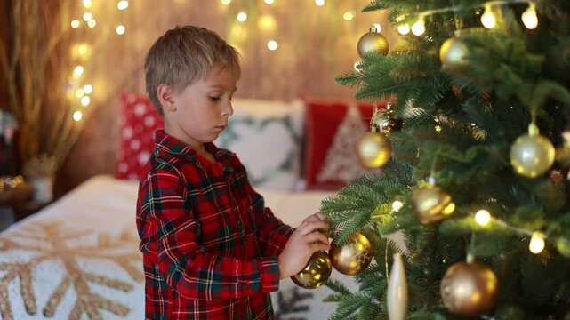 Cute blond child, boy, celebrating Christmas at home, decorated room for the holidays, child reading book and playing