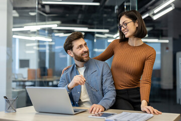 Woman flirts with man at workplace inside office, widows of employees smiling contentedly working...