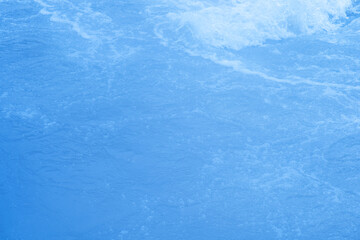 Blue water with ripples on the surface. Defocus blurred transparent blue colored clear calm water surface texture with splashes and bubbles. Water waves with shining pattern texture background.