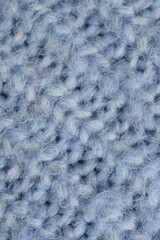 macro texture of woolen blue crocheted sweater as background, close-up of blue crocheted front surface, woolen texture of woolen wool, knitted front surface