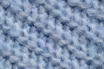 macro texture of woolen blue crocheted sweater as background, close-up of blue crocheted front surface, woolen texture of woolen wool, knitted front surface