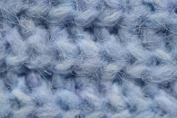 macro texture of woolen blue crocheted sweater as background, close-up of blue crocheted front surface, woolen texture of woolen wool, knitted front surface