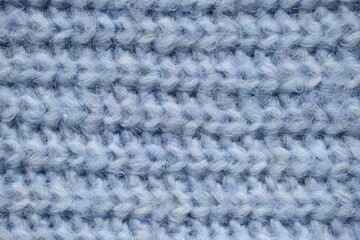 macro texture of woolen blue crocheted sweater as background, close-up of blue crocheted front surface, woolen texture of woolen wool, knitted front surface