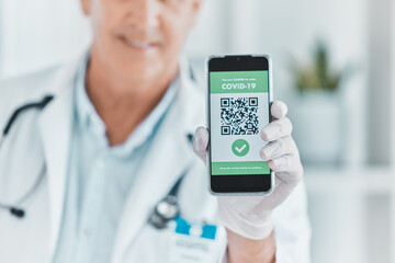 Doctor, hand and phone with QR code for covid 19, info or vaccine status in hospital. Healthcare, professional man or screen of mobile with barcode, scan or contactless payment option in consultation