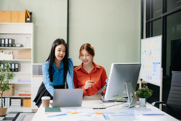 Obraz premium Two Asian businesswoman and man discuss investment project working and planning strategy with tablet laptop computer