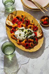 Appetizing italian burrata cheese with roasted mini bell pepper on yellow golden plate on a wooden background. Luxury Restaurant Food. Close up, copy space. Vertical