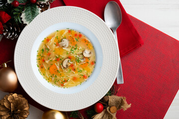 Short noodle soup with vegetables and mushrooms. Top view table with Christmas decoration.
