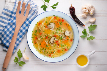 Short noodle soup with vegetables and mushrooms. Top view table with  decoration.