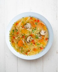 Short noodle soup with vegetables and mushrooms. Top view table with  decoration.