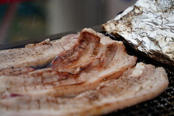 Close-up of pork belly being grilled on a charcoal grill.