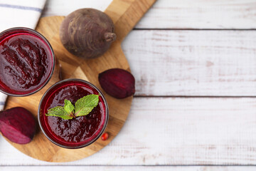 Fresh beetroot smoothie in glasses on white wooden table, flat lay. Space for text