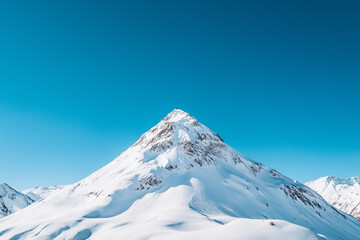 Majestic snow-covered mountain peak under a crisp, clear winter sky, showcasing the beauty of nature's extremes.