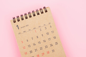 Brown calendar for January 2025 on pink background close-up, planning concept.