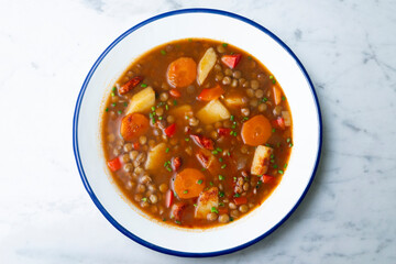 Spicy stewed lentils with vegetables and potatoes. Top view table with decoration.