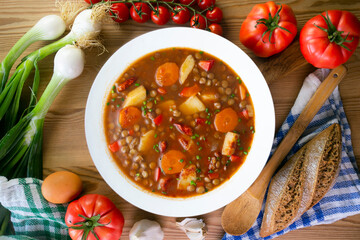 Spicy stewed lentils with vegetables and potatoes. Top view table with decoration.