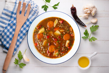 Spicy stewed lentils with vegetables and potatoes. Top view table with decoration.