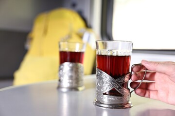 Young woman with cups of tea at table in train, closeup