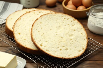 Tasty cut sponge cake and ingredients on wooden table, closeup