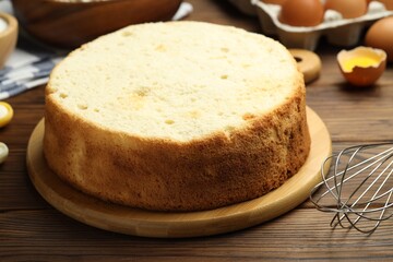 Tasty cut sponge cake, whisk and ingredients on wooden table