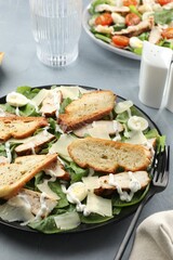 Delicious Caesar salad with chicken on grey textured table