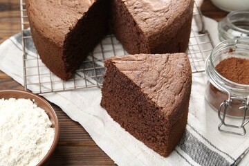 Cut chocolate sponge cake on wooden table, closeup