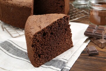 Piece of tasty chocolate sponge cake on wooden table, closeup