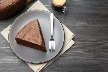 Piece of tasty chocolate sponge cake served on wooden table, flat lay