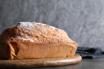 Tasty sponge cake with powdered sugar on grey table, closeup