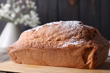 Tasty sponge cake with powdered sugar on table, closeup