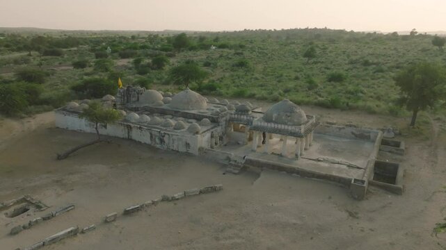 Drone circles around the ruins of Nagarparkar Jain temple with tourists sightseeing, wild deserted landscape in Sindh province