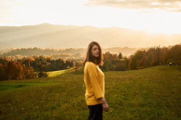 a portrait  young woman in mustard sweater in autumn mountains at sunset