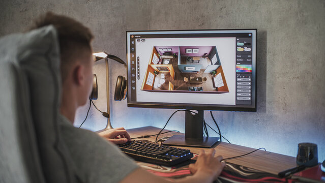 Young 3D designer creates and develops stylish house interior using PC and professional 3D modeling software or design app. Caucasian teenager works remotely on freelance project on computer at home.