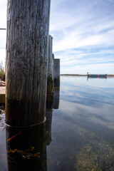 A wooden post is in the water with a boat in the background