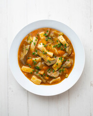 Squid stew with potatoes, artichokes and vegetables. Top view table with  decoration.